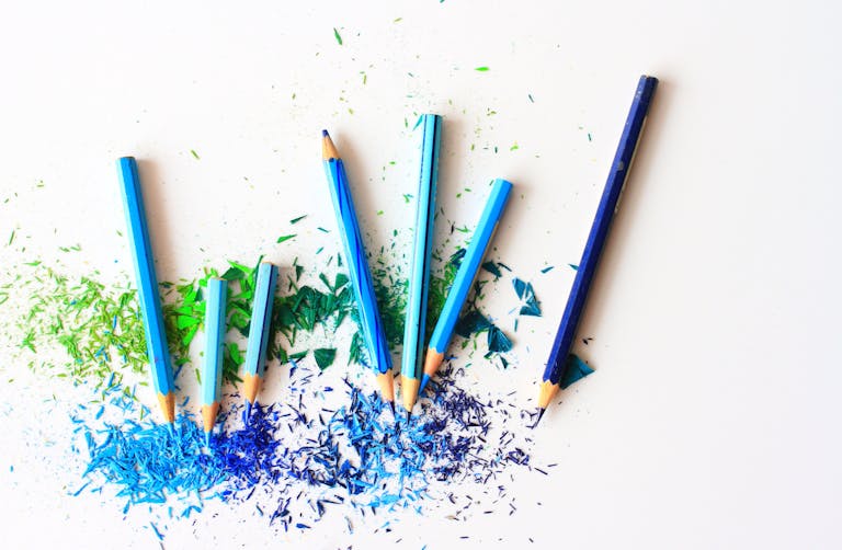 Creative display of colored pencils and vibrant shavings on a white background.